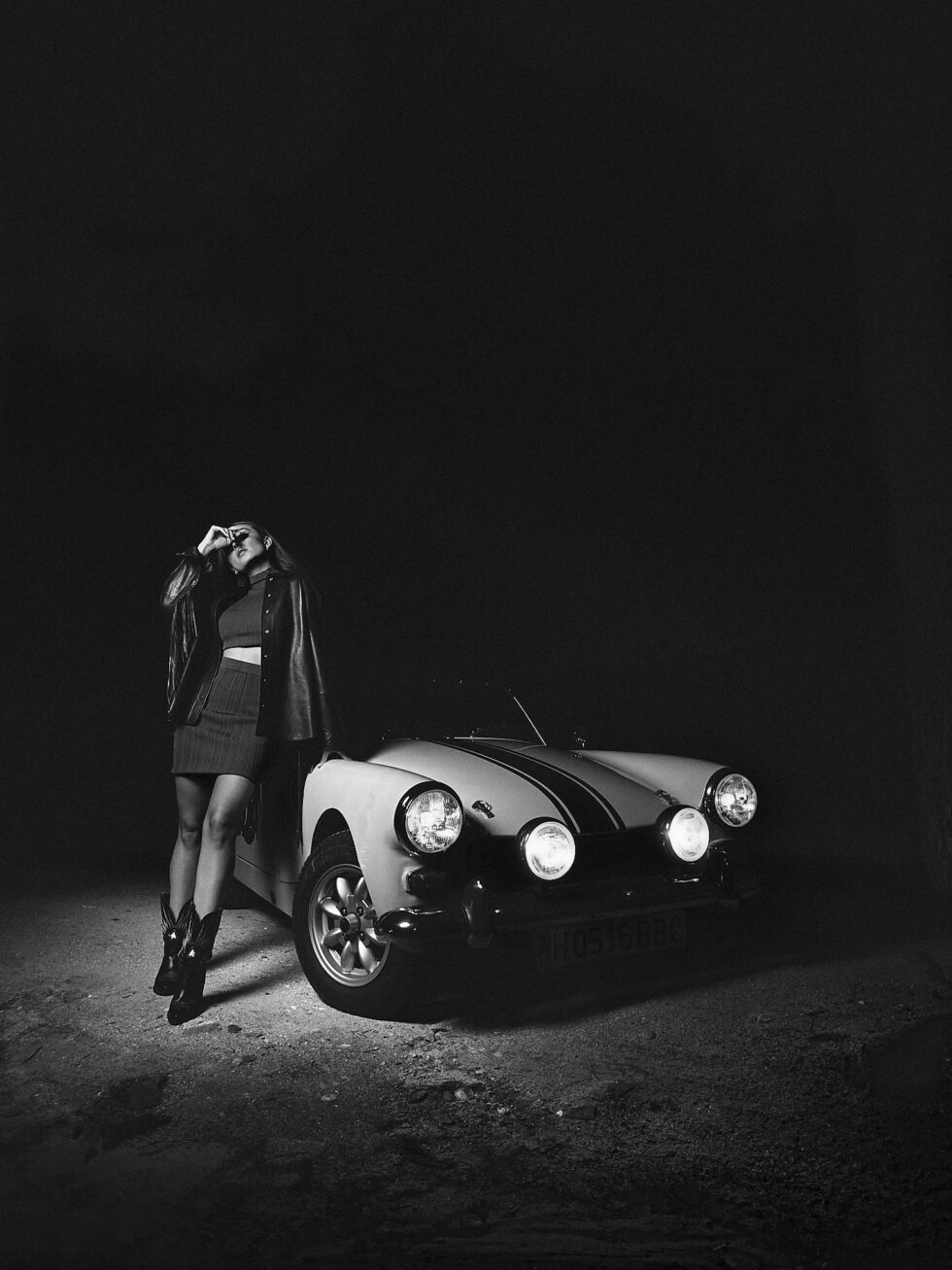 mujer años 70 apoyada en coche blanco y negro